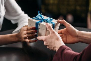 cropped shot of man giving anniversary gift to girlfriend