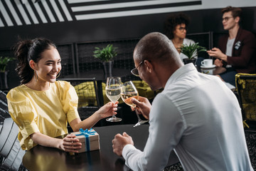 young couple celebrating anniversary of relationships and clinking glasses of wine