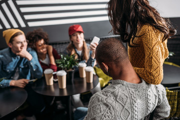 group of stylish friends spending time together in cafe