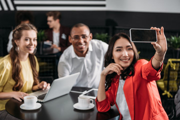group of young business partners taking selfie in cafe