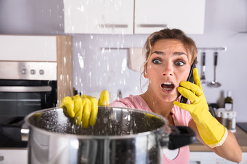 Woman Calling Plumber To Fix Water Leaking From Ceiling
