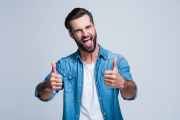 Great work! Handsome young man looking at camera with smile and gesturing thumb up while standing...