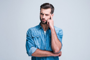 What have I forgot? Handsome young man looking confused while standing against white background