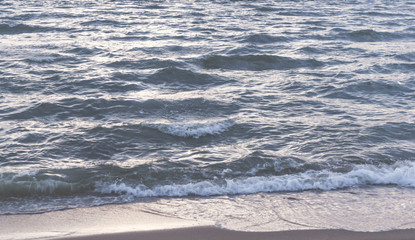 Naklejka na ściany i meble Wave crushing on to the beach with shining sun