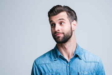 Nice thing! Portrait of handsome young man looking away while standing against white background