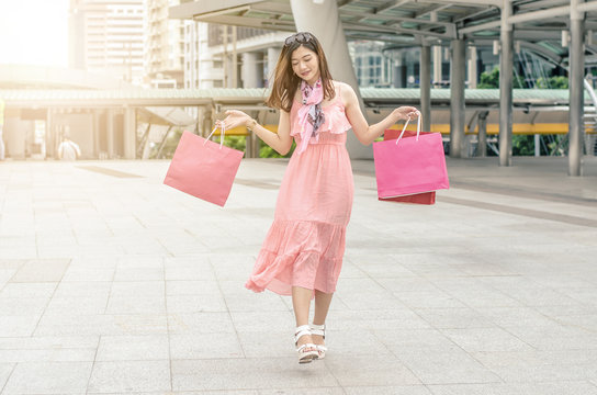 Shopping girl. Beautiful modern woman holding shopping bags. Background city