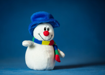 A cute little soft snowman with a blue hat and a colorful scarf