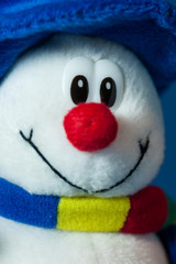 A cute little soft snowman with a blue hat and a colorful scarf