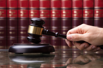 Person Striking Gavel On Sounding Block