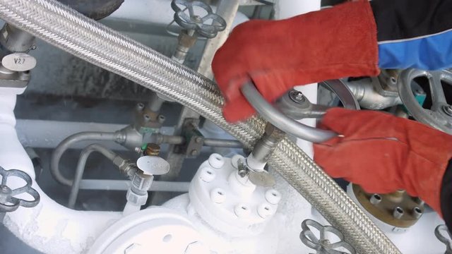 Worker in protective gloves turning cryogenic valve