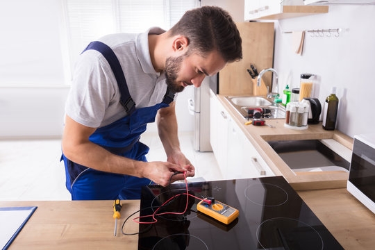 Young Repairman Fixing Induction Stove