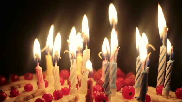 Birthday candles burning on a delicious fruit berry cake celebration