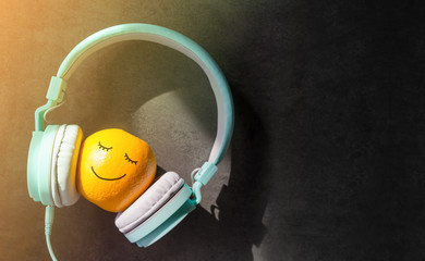 Relaxing in Summer with Music Concept, present by Orange Fruit Listening in Headphone, Happy Smiley Face Drawn on Skin