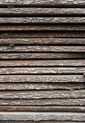 Folded wooden brown and gray planks in a sawmill. Piled alder boards as texture for design.