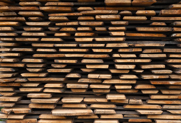 Folded wooden brown and gray planks in a sawmill. Piled alder boards as texture for design.