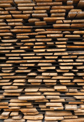 Folded wooden brown and gray planks in a sawmill. Piled alder boards as texture for design.