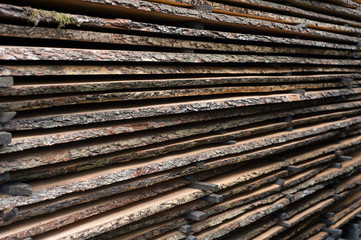 Folded wooden brown and gray planks in a sawmill. Piled alder boards as texture for design.