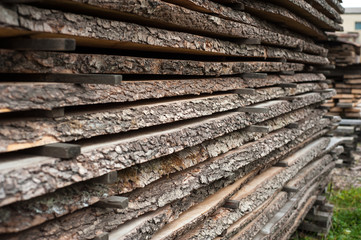 Folded wooden brown and gray planks in a sawmill. Piled alder boards as texture for design.
