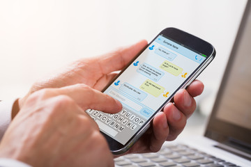 Businessperson Sending Text Message From Mobile Phone