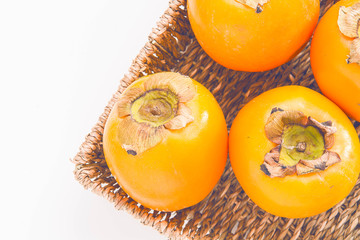 Kaki fruits in the basket on white background.