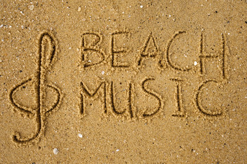 Music key and text beach music drawn on a yellow sand.