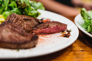 Close up stir fried beef steak served with vegetable side dish and salad topping with balsamic dressing.