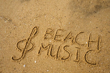 Music key and text beach music drawn on a yellow sand.