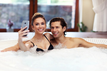 Happy couple enjoying jacuzzi in hotel spa