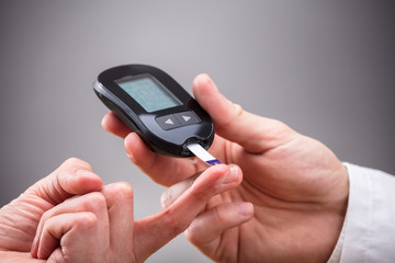 Doctor Checking Patient's Sugar Level With Glucometer