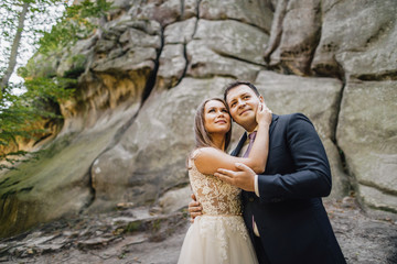 Young bride and groom walking high in mountains. Amazing weather with fog and sun