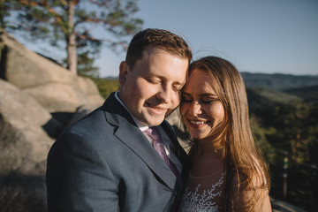 Young bride and groom walking high in mountains. Amazing weather with fog and sun