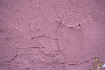 A fragment of a pink wall with scratches and cracks