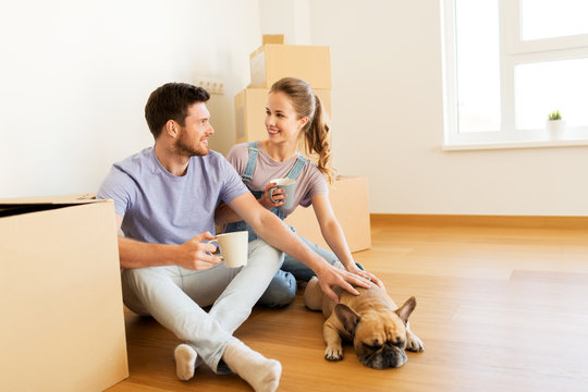 happy couple with boxes and dog moving to new home
