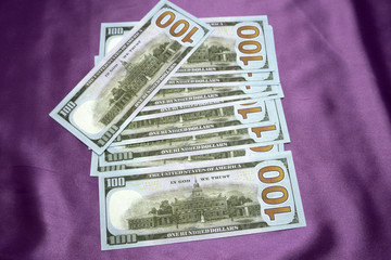 100 dollars banknotes on a purple background.
