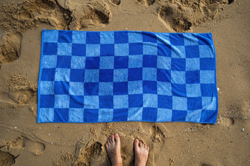 Blue towel on sandy beach. Concept of having good vacation in warm tropical country