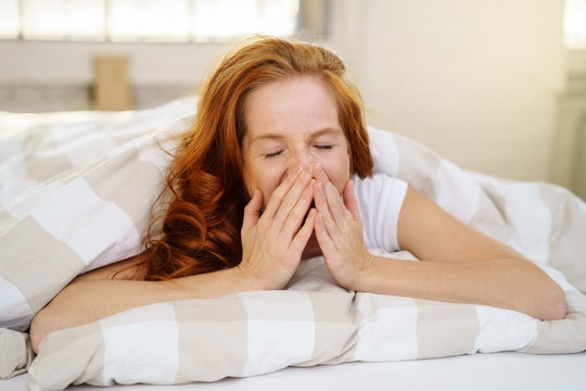 frau liegt im bett und g&auml;hnt