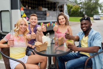 happy friends with drinks eating at food truck