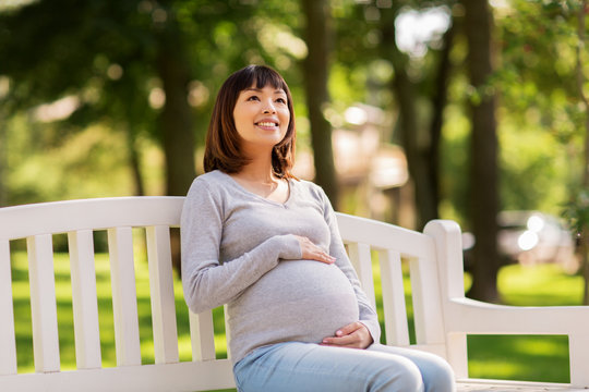 Happy Pregnant Asian Woman Sitting On Park Bench