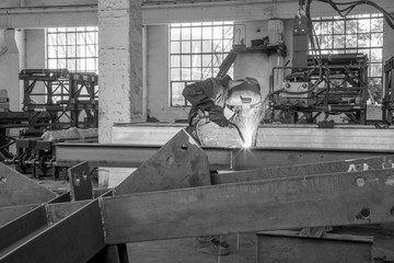Naklejka na ściany i meble monochrome photo of a worker performing gas welding work
