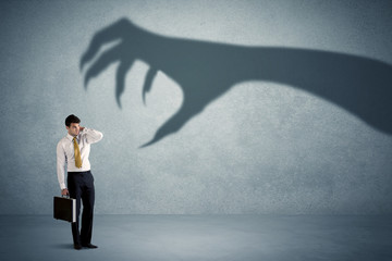 Fototapeta premium Business person afraid of a big monster claw shadow concept