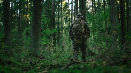 Shot of a Fully Equipped Soldier Moving Further in the Dense Forest. He's on the Reconnaisance...