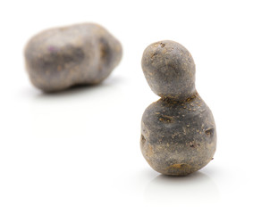 Vitelotte potatoes isolated on white background thinking stones composition.
