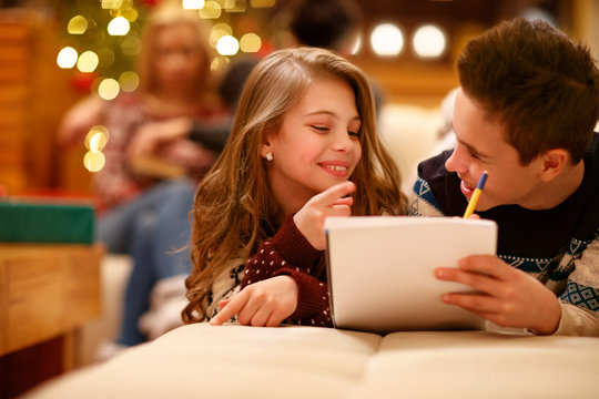 Girl with boy writing Christmas wishes
