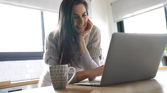 Middle-aged woman connected on internet with laptop at home