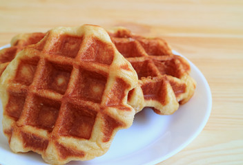 Closed up a pair of Belgian Waffle on White Plate Served on Wooden Table 