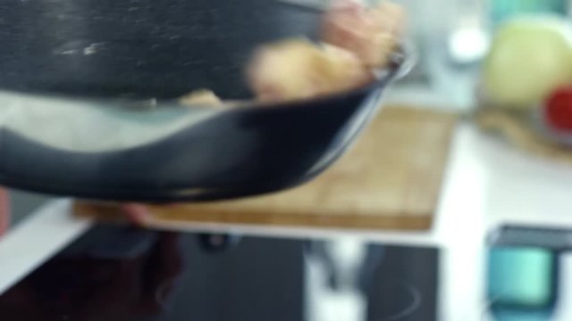 Close up of unrecognizable male cook tossing hot pan with chopped bacon sizzling in olive oil