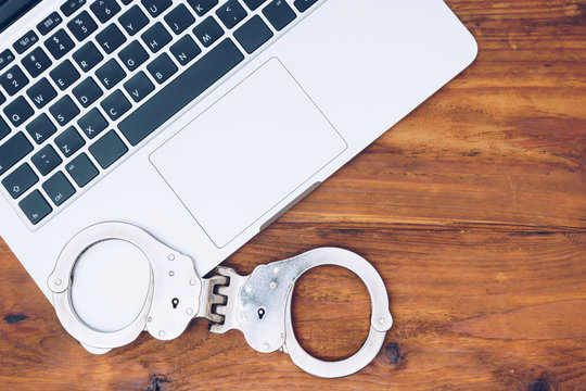 Handcuffs on latop keyboard, Concept of internet crime, hacking and cyber crimes