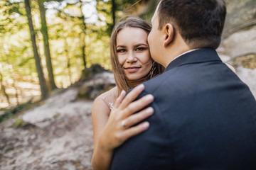 Fototapeta premium Young bride and groom walking high in mountains. Amazing weather with fog and sun
