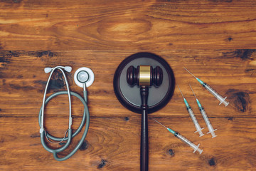 Syringes, stethoscope and  judge gavel on wooden background.