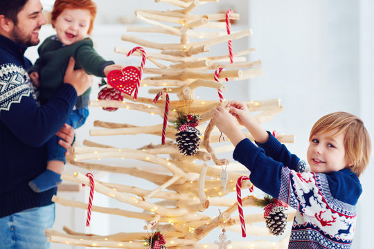 family decorates an extraordinary christmas tree made of branches and driftwood at home